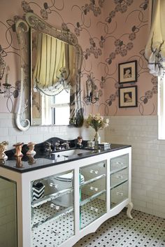 a bathroom with two sinks and a large mirror on it's sideboard, in front of a floral wallpapered wall