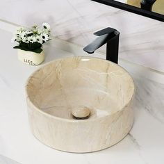 a bathroom sink sitting on top of a white counter next to a vase with flowers