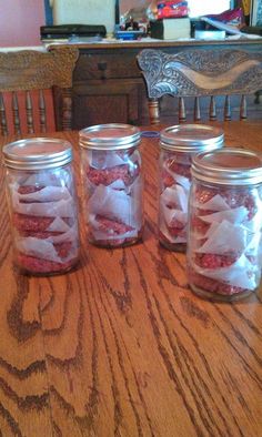 four jars filled with food sitting on top of a wooden table