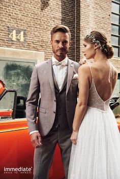 a man and woman standing next to an orange car