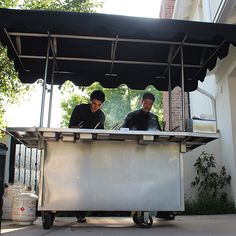 two men sitting at an outdoor food cart