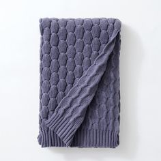 a purple knitted blanket laying on top of a white wall