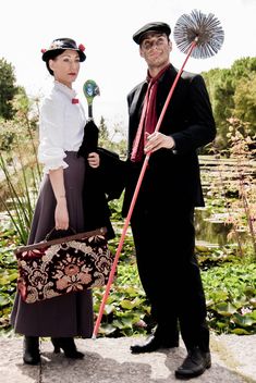 a man and woman are dressed up in period costumes, holding parasols while standing next to each other