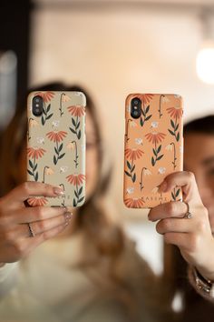 two women holding up cell phones in their hands