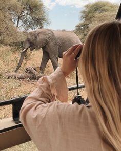 a woman is looking at an elephant in the distance