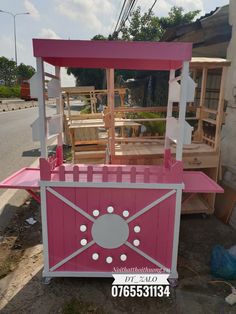 a pink and white cart sitting on the side of a road next to a building