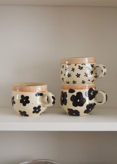 two coffee cups sitting on top of a shelf