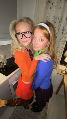 two young women hugging each other in the kitchen, one with glasses on her head