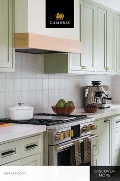 a kitchen with green cabinets and white countertops has a black sign that says cameraia above the stove