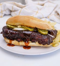 a steak sandwich with pickles and onions on a bun