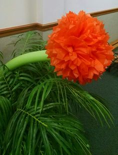 an orange flower sitting on top of a green plant