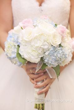 a bride holding a bouquet of white and blue flowers