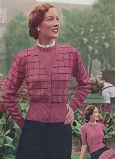 a woman standing in front of a garden filled with flowers and people sitting on the ground