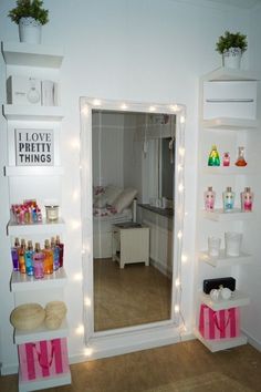 there is a mirror in the room with lights on it and shelves holding cosmetics products