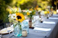 a long table is set with sunflowers and wine glasses