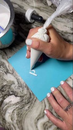 a woman's hands with white nail polish on top of a blue piece of paper