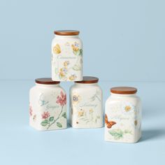 four ceramic jars with flowers and butterflies painted on them