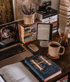 a laptop computer sitting on top of a wooden desk next to a pile of books