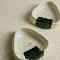 two black and white bowls sitting on top of a carpeted floor next to each other