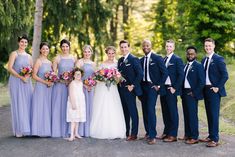 a group of people standing next to each other in front of some trees and grass