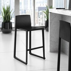 a black chair sitting on top of a white tile floor next to a table and potted plant