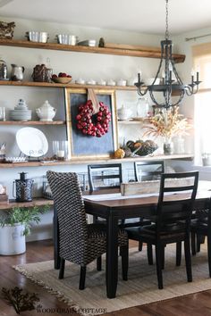 a dining room table with chairs and a wreath on the wall above it in front of a window