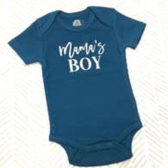 "Mama's Boy" Applied To A 100% Certified Organic Cotton Onesie With Commercial Heat Transfer Vinyl. Content And Care: 100% Organic Cotton. Handmade In The Usa, Machine Washable. Blue Tops With Name Print For Spring, Summer Blue Tops With Name Print, Cute Blue Tops For Family Occasions, Blue Cotton T-shirt For Mother's Day, Family Matching Blue Tops With Name Print, Blue Cotton T-shirt For Gender Reveal, Blue Tops For Summer Gender Reveal, Blue Cotton Tops With Name Print