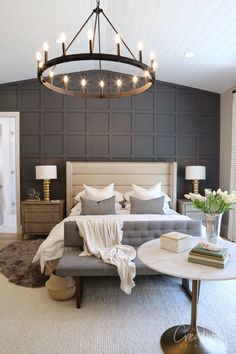 a large bed sitting under a chandelier next to a table with books on it