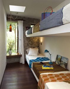 two bunk beds in a small room with wood flooring and white walls, along with windows