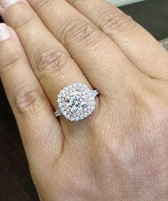 a woman's hand with a diamond ring on top of her finger and the other hand holding an engagement ring