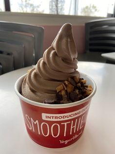 an ice cream sundae with chocolate and nuts in it's cup on a table