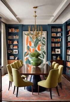 an elegant dining room with blue walls and yellow chairs in front of a large painting on the wall