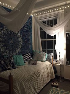 a bedroom with white curtains, blue and green decor and lights on the windowsill