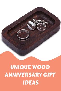 two wedding rings in a wooden tray with the words unique wood anniversary gift ideas on it