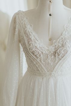 a white dress is on display in front of a mannequin's head