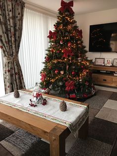 a living room with a christmas tree in the corner and decorations on the coffee table