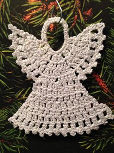 a crocheted angel ornament hanging from a christmas tree with pine needles