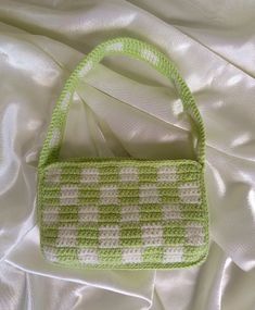 a green and white purse sitting on top of a bed