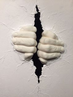 two white hands sticking out of a hole in the wall with paint peeling off it