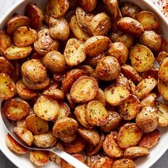 a white bowl filled with roasted potatoes on top of a table