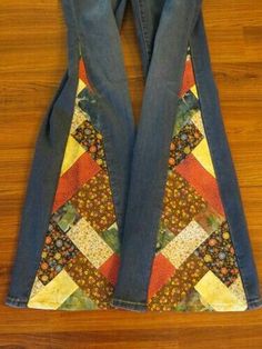 the back end of a pair of jeans with patchwork on them, sitting on top of a wooden floor