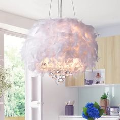 a white chandelier hanging from a ceiling in a kitchen with blue flowers on the counter