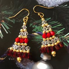 red and gold beaded christmas tree earrings on top of a silver ornament