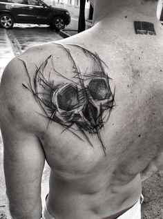 a man's back with a skull tattoo on his left shoulder and an eyeball in the middle