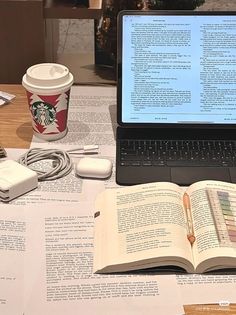 an open laptop computer sitting on top of a table next to a cup of coffee