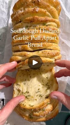 someone holding a sandwich with garlic pull apart bread