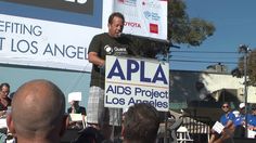 a man standing at a podium in front of a sign that reads apla aids project los angeles