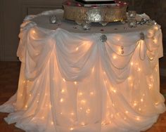 a table topped with a cake covered in white frosting and lite up lights