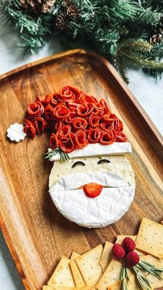 a wooden tray topped with crackers and cheese covered in santa claus's face