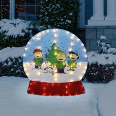 a lighted snow globe with three cartoon characters on it in the middle of a snowy yard